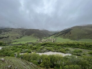View of the medieval Targim tower complex in the Caucasus mountains surrounded by greenery. The...