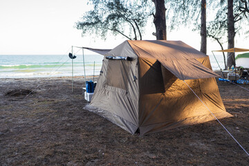 Tourists camping in tents under trees on the beach.