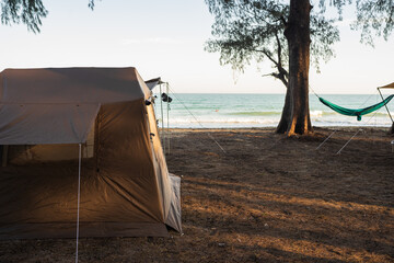 Tourists camping in tents under trees on the beach.