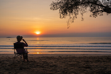 women sit on a chair on the beach with beautiful sea and sunrise sky, .Outdoor lifestyle concept.
