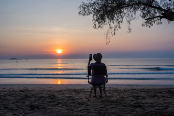 women sit on a chair on the beach with beautiful sea and sunrise sky, .Outdoor lifestyle concept.
