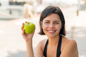 Young pretty Bulgarian woman at outdoors with an apple