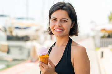 Young pretty Bulgarian woman with a cornet ice cream at outdoors smiling a lot