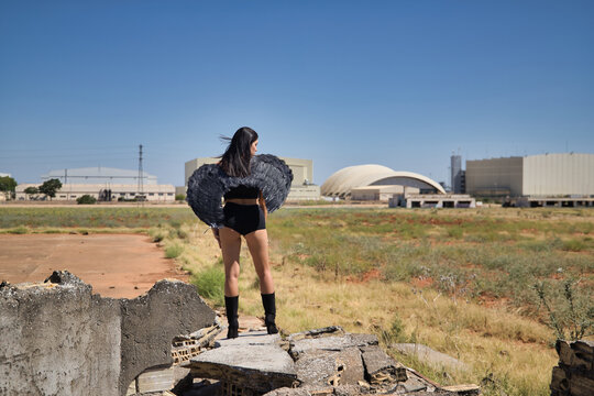 South American woman, young, beautiful, brunette with lingerie and black wings, posing on her back with the wind ruffling her hair amidst the ruins of a building. Concept angels, beauty, costumes.