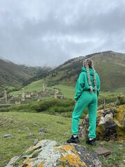 A girl on the background of the medieval Targim tower complex in the Caucasus mountains, surrounded...