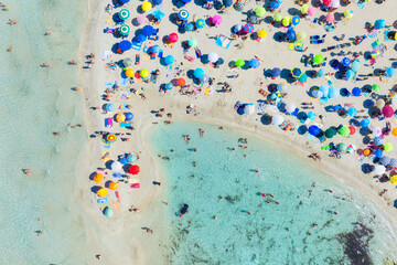 Top view from drone at beach and azure sea. Aerial view on beach, people and umbrellas.  Europe, Mediterranean Sea. View on the coast from drone.