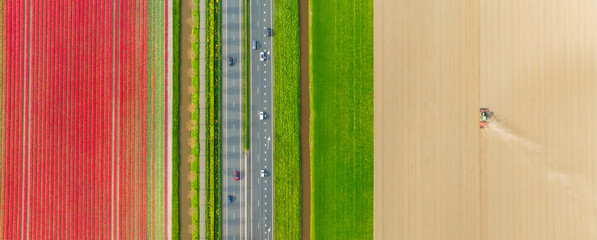 Drone view of a road in the middle of a field. Landscape from a drone. Road and transport. Agricultural transport. Tractor in the field. View from above. Agriculture and growing plants. - 790660664