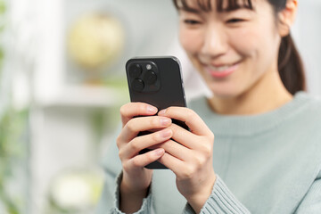 リビングでスマートフォンを操作する女性