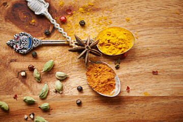 Spoons, spice and selection of seasoning for cooking on kitchen table, turmeric and cardamom for meal. Top view, condiments and options for spicy gourmet in Indian culture, art and food preparation