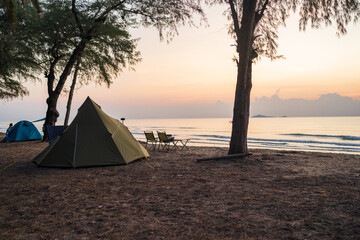 Morning sunrise beside camp and tents under tree, golden light at sea, Outdoor lifestyle concept.
