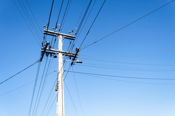 Low angle view of power post and powerlines against a cloudless blue sky. Auckland. - 790665656