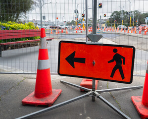 Man Walking Road sign in front of a closed footpath. Traffic cones and fences along the road. Roadworks in Auckland. - 790665821
