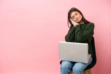 Young caucasian woman sitting on a chair with her laptop isolated on pink background making sleep gesture in dorable expression - 790669201