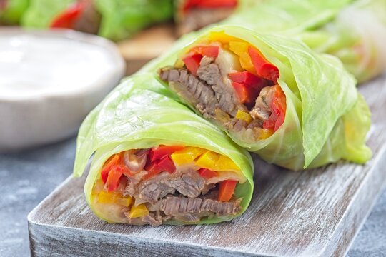 Closeup cut of beef and vegetable cabbage leaves wraps, served with plain yogurt, horizontal