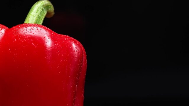 Macrography of a red bell pepper against a sleek black background takes center stage. Each close-up shot meticulously captures the intricate details and textures of the pepper. Close up. Comestible.
