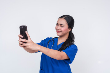 Asian female caregiver in blue scrubs takes a selfie, isolated on white