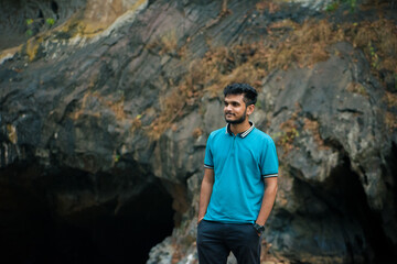 Young indian man wearing blue t-shirt standing in a cave.