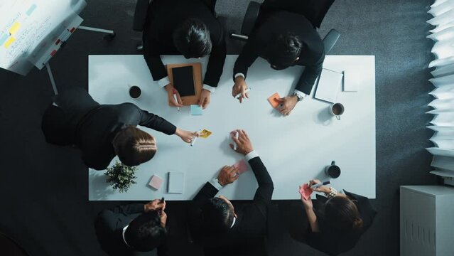 Top down aerial view of professional business people writing and sharing marketing idea on sticky note. Group of diverse executive manager working together or brainstorming strategy. Directorate.