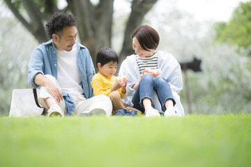 公園でピクニックをする家族 春夏のお出かけやレジャーのイメージ