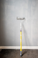 Paint roller extendable pole over painted woodchip wallpaper wall during home renovation in england...