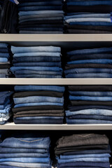 Stacks of jeans on shelves in a fashion store. jeans clothes on shelf in shop.