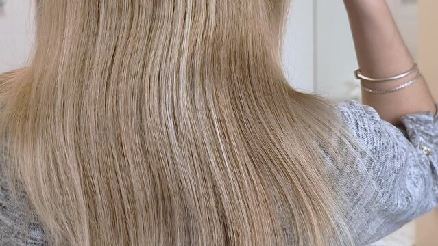 Blonde Frau, die sich mit einer B&uuml;rste die Haare k&auml;mmt