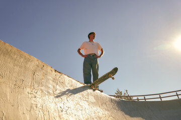 Young skateboarder standing with his board on the ramp of a skate park. Active lifestyle concept