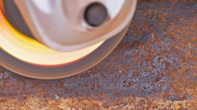 rusted metal surface is being cleaned with angle grinder and a flap disc, full-frame closeup with slow motion