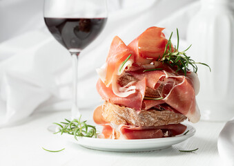 Ciabatta with prosciutto, rosemary and glass of red wine.
