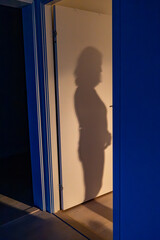 A woman's shadow in the doorway of a bedroom in an apartment.