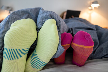 A man and women's feet under a comforter in a bedroom.