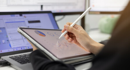 close up manager woman hand using stylus pen to pointing on tablet screen to show company profit and roi summary monthly in the private room for business strategy concept