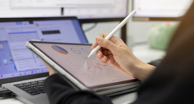 close up manager woman hand using stylus pen to pointing on tablet screen to show company profit and roi summary monthly in the private room for business strategy concept