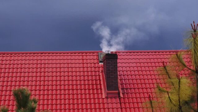 House roof with brick chimney emitting dense smoke into the atmosphere