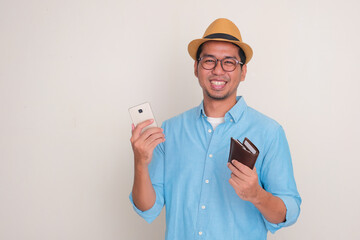 A man smiling happy at the camera while holding cellphone and wallet