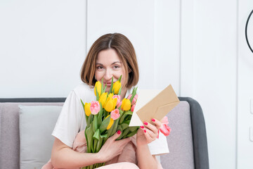 A young beautiful girl received a bouquet of flowers and a congratulatory letter on a wonderful World Women's Day. She sits and reads the letter and thanks the sender