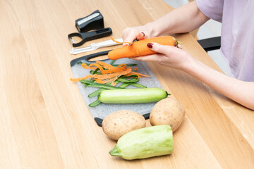 Close-up shot of a woman peeling vegetables using special vegetable peelers in the kitchen	