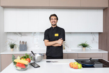 Young handsome male chef in cooking in the kitchen	 - obrazy, fototapety, plakaty