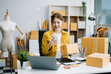 Young business owner woman prepare parcel box and standing check online orders for deliver to...