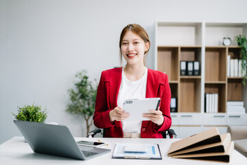 Confident Asian woman with a smile standing holding notepad and tablet at the ffice..