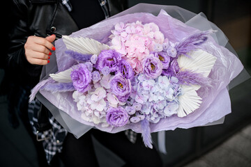 Close-up photo of a large bouquet of purple flowers in a woman's hands