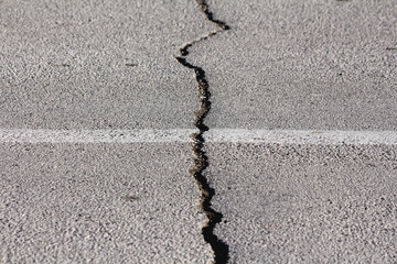 Large crack on public paved asphalt road that appeared after big earthquake waiting to be filled...