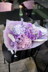 Large bouquet of various purple flowers lies on a black chair