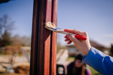 Valmiera, Latvia - April 21, 2024 - A close-up of a hand painting a wooden beam with a brush, in...