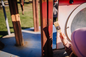 Valmiera, Latvia - April 21, 2024 - A person's hand applying paint with a brush to a wooden pole,...