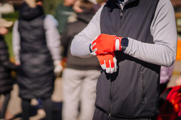 Valmiera, Latvia - April 21, 2024 - A person putting on red gloves, with others in the blurry...