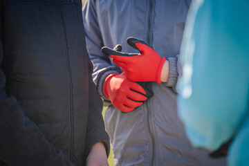 Valmiera, Latvia - April 21, 2024 - Two people holding hands, one wearing bright red work gloves,...