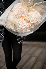 Close up of huge bouquet of white hydrangeas and white roses wrapped in white gift paper