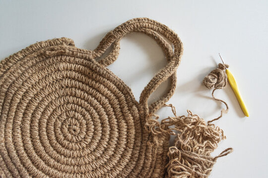 Round knitted bag made of twine, thread and 2mm hook for knitting on a white background