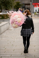 Young slim woman holding a huge bouquet of white and pink hydrangeas and peonies on her shoulder